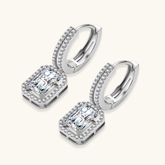 Sterling silver huggie hoops with emerald-cut moissanite drops featuring pavΓ©-set crystals on white background.