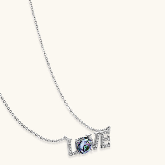Sterling silver LOVE necklace with brilliant moissanite center stone and pavΓ© details on neutral background.