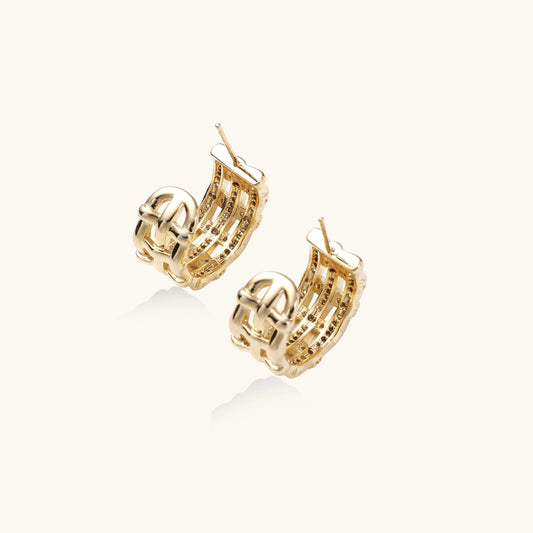 Gold-plated geometric hoop earrings with basket-weave lattice design and pavΓ© crystal accents on cream background