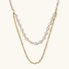 Layered gold chain necklace with organic baroque freshwater pearls and adjustable length on cream background