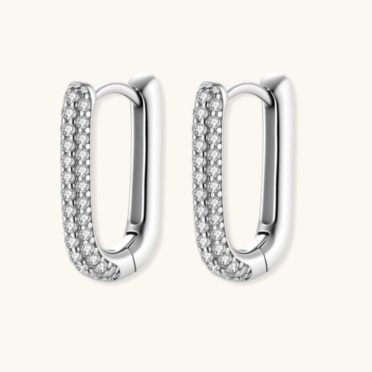 Close-up of platinum-plated sterling silver huggie hoops with pavΓ© crystal setting on white background.