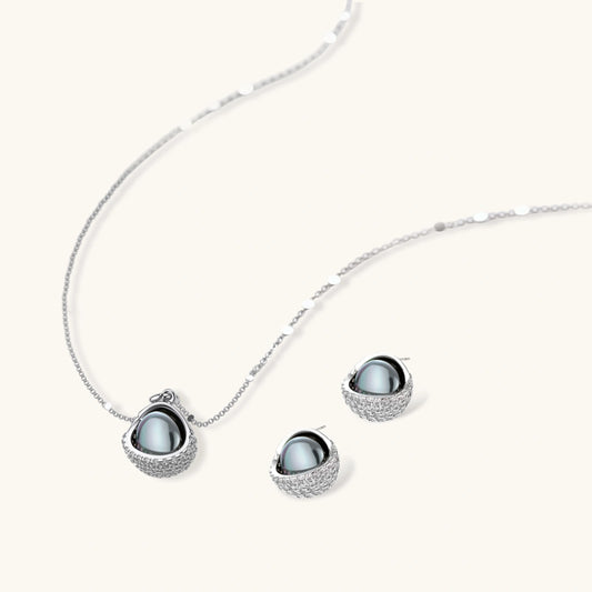 White gold plated spherical jewelry set with zirconia crystal pavΓ© and dark lustrous centers on neutral background.