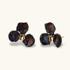 Dark iridescent baroque pearls arranged in flower pattern with 18K gold-plated center on cream background.
