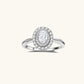 Sterling silver ring with oval moissanite center stone surrounded by double halo of sparkling stones on neutral background.