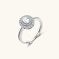 Sterling silver ring with oval moissanite center stone surrounded by double halo of sparkling stones on neutral background.