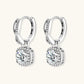 Sterling silver twisted hoop earrings with round moissanite stones in halo settings against neutral background.