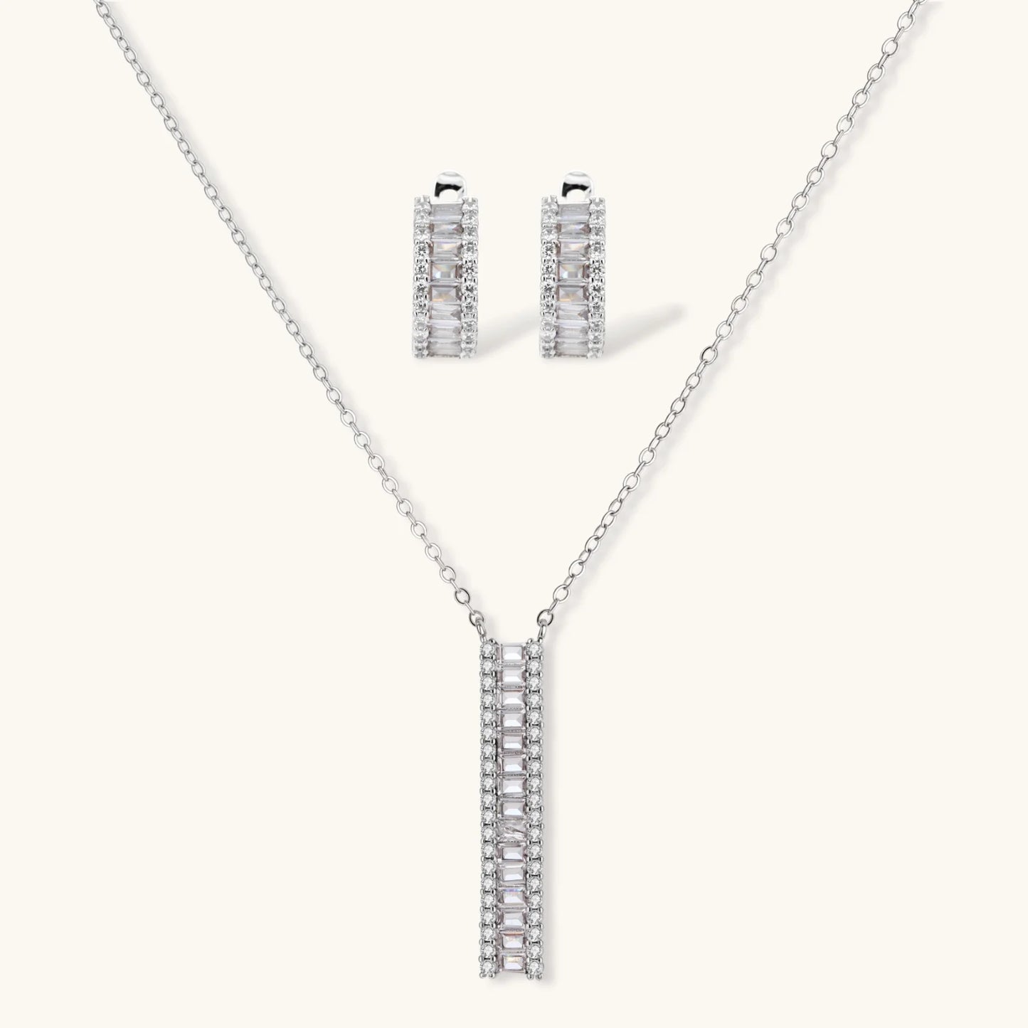 White gold plated necklace with vertical cubic zirconia pendant and matching hoop earrings on neutral background