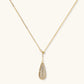 Gold-plated teardrop necklace and earrings covered in AAA cubic zirconia crystals on cream background.