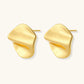 Close-up of organic gold-plated sterling silver stud earrings with flowing sculptural design and curved cut-outs