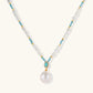 Beaded necklace with baroque pearls, turquoise stones, and gold accents featuring a large pearl pendant on white background.