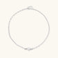 Dainty rhodium-plated silver chain necklace with centered 10mm freshwater pearl and crystal accents on cream background