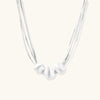 Sterling silver multi-strand necklace with three brushed round beads on cream background