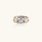 Two-tone ring with brushed silver center, gold beaded edges, and blue zirconia stones on white background.