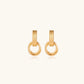 Gold stud earrings with vertical ridged bar connecting to triple interlocking circular rings on white background