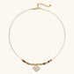 Gold-toned beaded necklace with grey stones and quatrefoil abalone shell pendant on cream background.