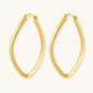 Set of geometric gold-plated sterling silver hoop earrings in oval and cushion shapes on cream background