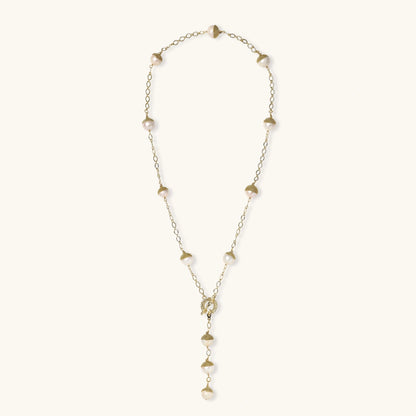Gold-plated lariat necklace with baroque pearls and textured caps on cream background, showing adjustable Y-shaped design.