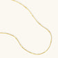 Delicate gold-plated sterling silver chain necklace with geometric segments displayed against cream background