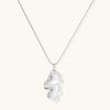 Modern sculptural pendant necklace with twisted metallic design on delicate silver chain against neutral background.