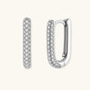 Close-up of platinum-plated sterling silver huggie hoops with pavé crystal setting on white background.