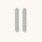 Close-up of platinum-plated sterling silver huggie hoops with pavé crystal setting on white background.