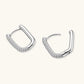 Close-up of platinum-plated sterling silver huggie hoops with pavé crystal setting on white background.