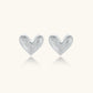 Pair of brushed platinum-plated 925 sterling silver puffy heart stud earrings on a cream background.