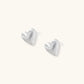 Pair of brushed platinum-plated 925 sterling silver puffy heart stud earrings on a cream background.