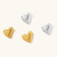 Pair of brushed platinum-plated 925 sterling silver puffy heart stud earrings on a cream background.