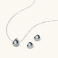 White gold plated spherical jewelry set with zirconia crystal pavé and dark lustrous centers on neutral background.
