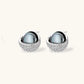 White gold plated spherical jewelry set with zirconia crystal pavé and dark lustrous centers on neutral background.