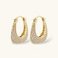 Gold-plated hoop earrings fully covered in sparkling zircon crystals with hinged closure on neutral background