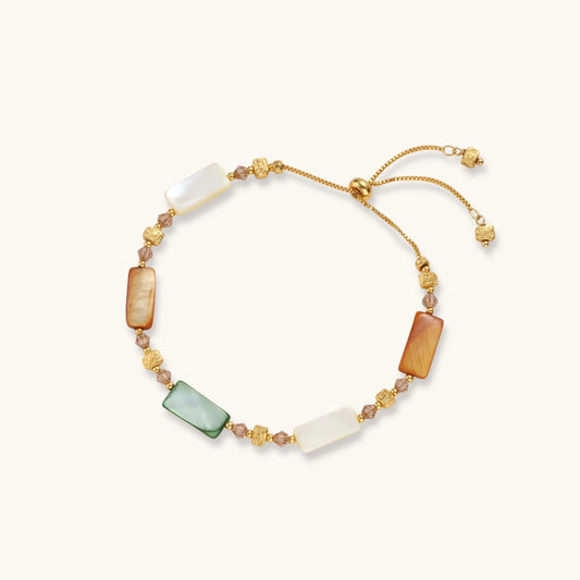 Adjustable gold-plated bracelet featuring rectangular shell beads in green, orange, and white tones on cream background.