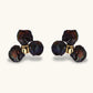 Dark iridescent baroque pearls arranged in flower pattern with 18K gold-plated center on cream background.
