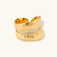 Adjustable gold-plated cuff ring with parallel ridged texture and diagonal row of sparkling zirconia stones on white background.